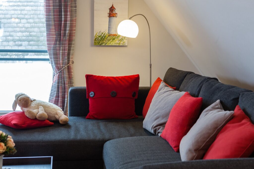 Sofa mit roten Kissen in Ferienwohnung Wenningstedt