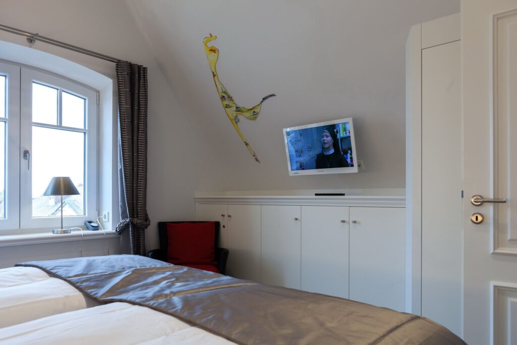 Schlafzimmer mit TV in Ferienwohnung Wenningstedt