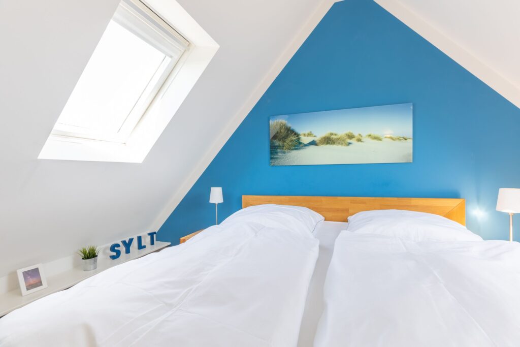 Schlafzimmer mit blauer Wand in Ferienwohnung Wenningstedt