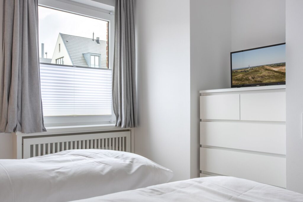 Schlafzimmer mit TV in Ferienwohnung Wenningstedt