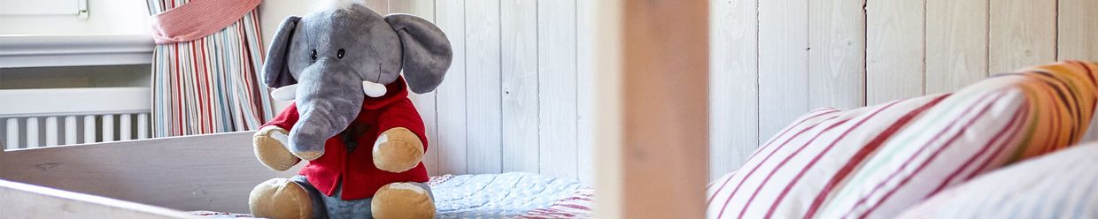Plüschtierelefant sitzt auf einem Kinderbett
