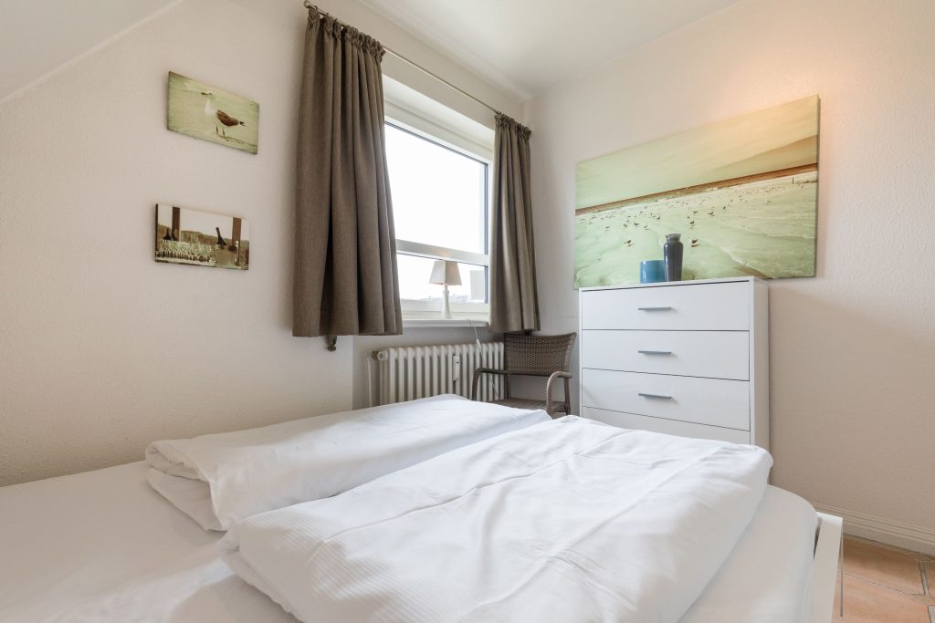 Schlafzimmer einer Sylter Ferienwohnung in beige und weiß gehalten