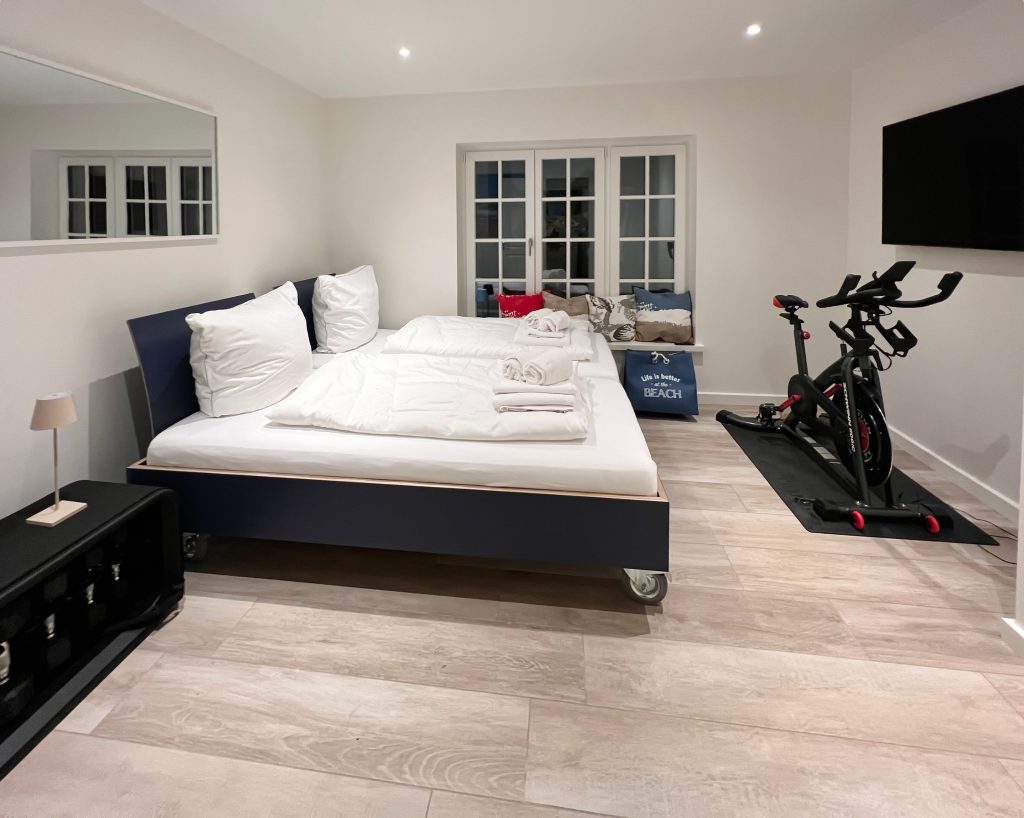 Bett mit Spinning-Rad und Fernseher in Ferienwohnung auf Sylt