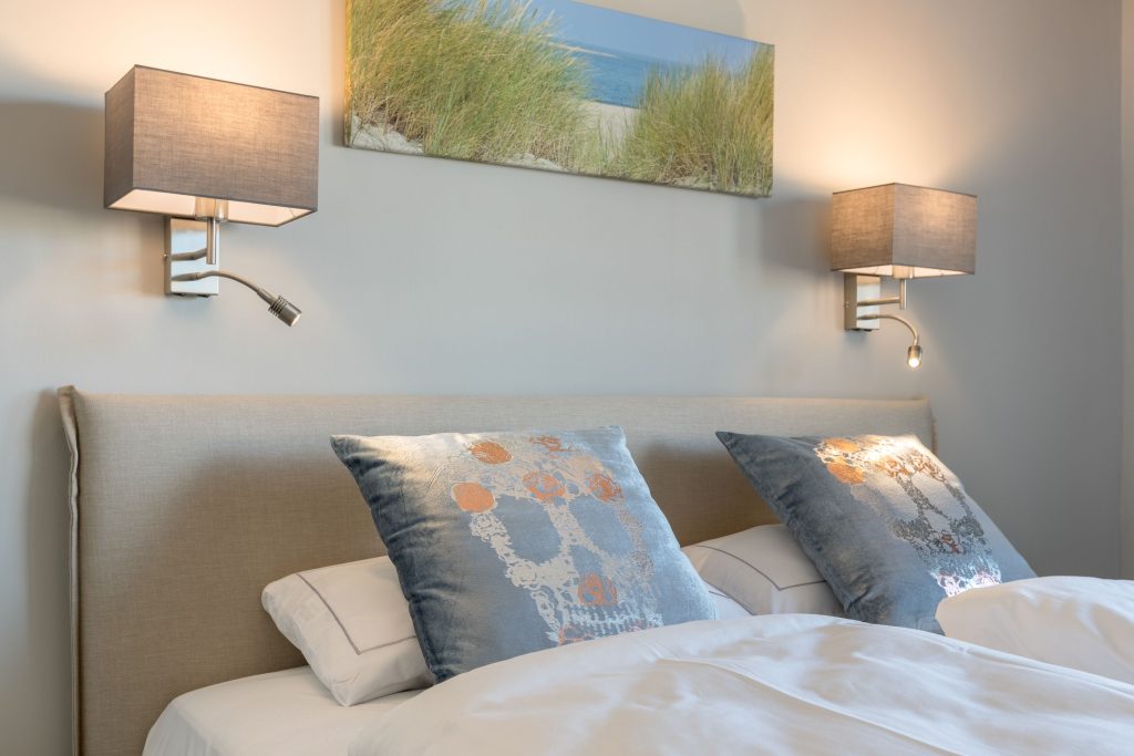 Doppelbett mit Lampen und Bild in Ferienwohnung auf Sylt