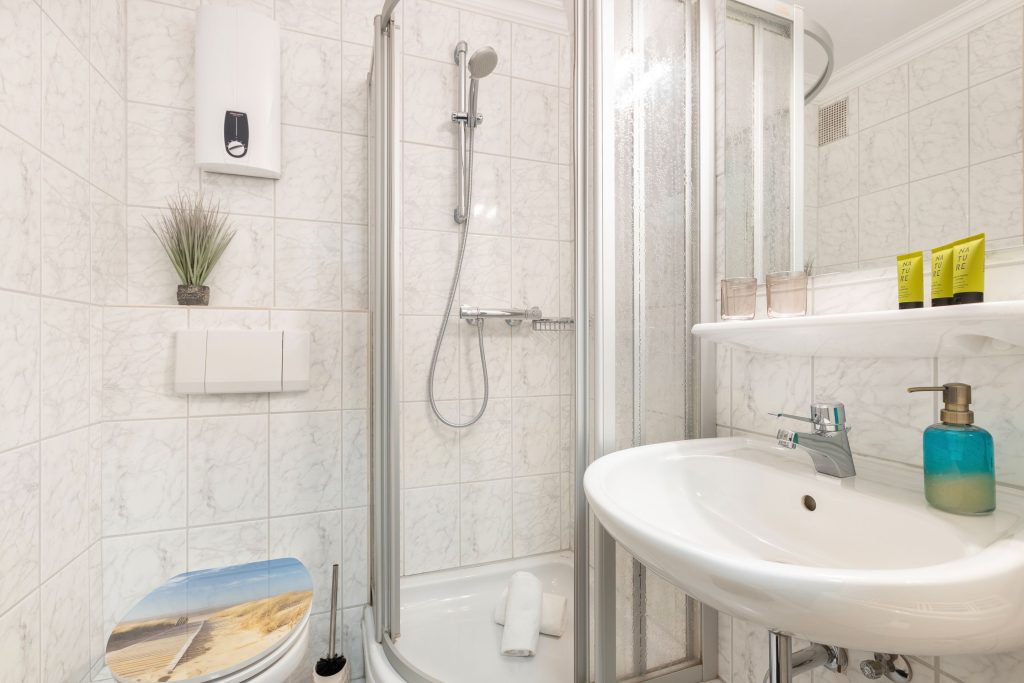 Gefliestes Badezimmer mit Toilette und Dusche in Ferienwohnung auf Sylt
