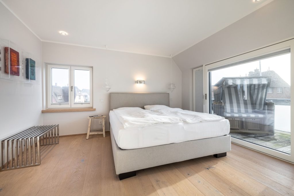 komfortables Bett im Schlafzimmer mit Balkon in Ferienwohnung auf Sylt