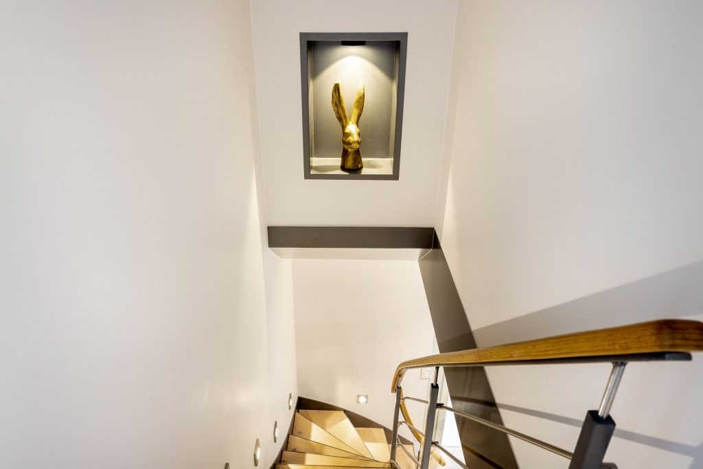 Treppenhaus mit goldener Hasendeko in Ferienwohnung auf Sylt
