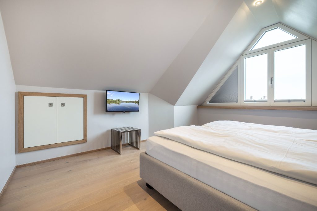 Schlafzimmer mit kleinem Fernseher und Bett auf Sylt